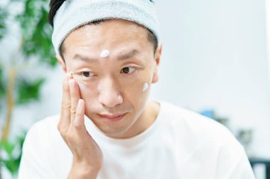 Erkekler odada yüzlerine nemlendirici krem sürüyor.