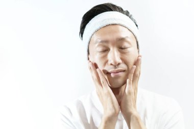 Orta yaşlı bir adam yüzüne dokunuyor.