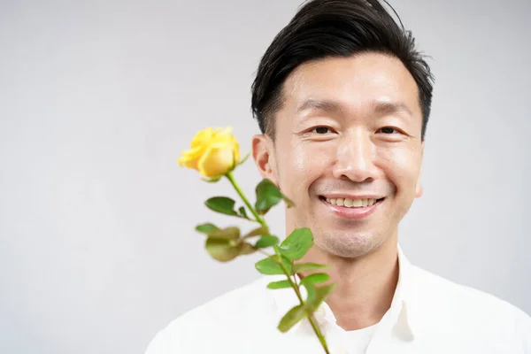 黄色いバラの花で微笑むアジア人男性 — ストック写真