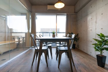 Oturma odasındaki pencerenin yanına bir tahta masa ve sandalyeler.