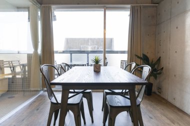 Oturma odasındaki pencerenin yanına bir tahta masa ve sandalyeler.