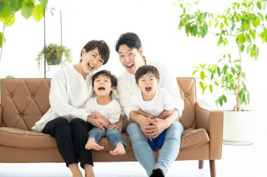 Asyalı bir aile kanepede oynaşıyor. 
