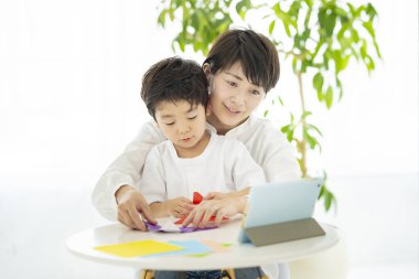 Anne ve çocuk tablete bakarken origami yapıyorlar.