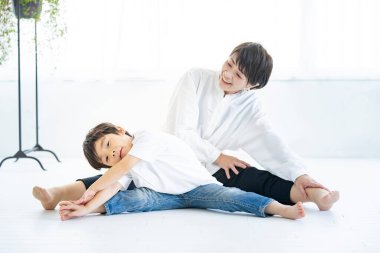 Asyalı anne ve oğlu yoga yapıyor.
