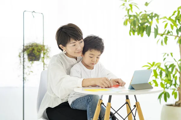 妈妈和孩子一边做折纸一边看平板电脑 — 图库照片