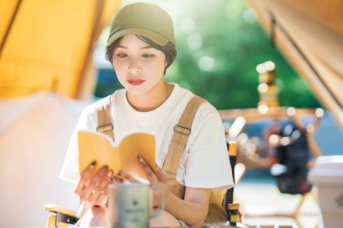 Tek kişilik kamp imajı. Kitap okuyan genç bir kadın. 