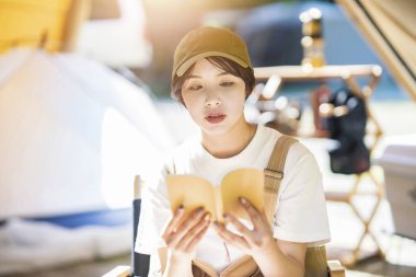 Tek kişilik kamp imajı. Kitap okuyan genç bir kadın. 