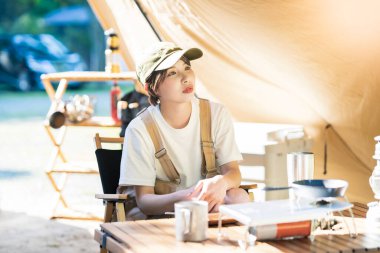 Solo kamp görüntüsü. Çadırda dinlenen genç bir kadın.