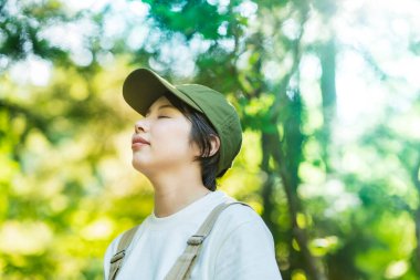 Bir kadın güzel bir günde ağaçlara bakıyor.