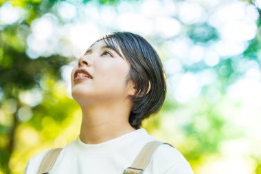 Bir kadın güzel bir günde ağaçlara bakıyor.