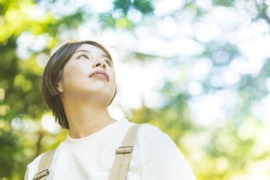 Bir kadın güzel bir günde ağaçlara bakıyor.