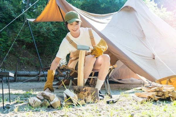 Solo kamp görüntüsü - odun kesen genç bir kadın