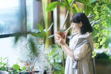 Çiçeklere gülümseyen genç bir kadın.