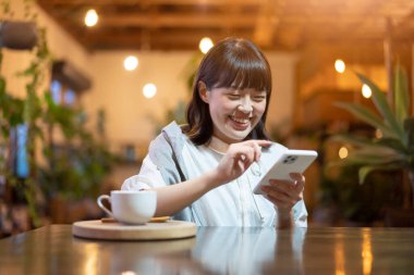 Sıcak bir atmosferde akıllı telefon ekranına bakan genç bir kadın.