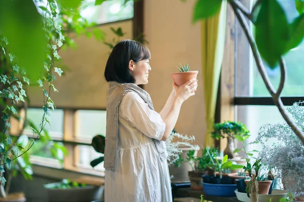 Ung Kvinna Tittar Bladväxterna Med Ett Leende — Stockfoto