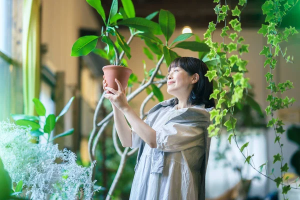 Ung Kvinna Tittar Bladväxterna Med Ett Leende — Stockfoto