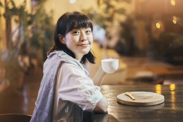 暖かい雰囲気の中でコーヒーを飲む若い女性 — ストック写真