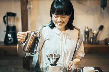 Rahatlatıcı bir yerde kahve yapan genç bir kadın.