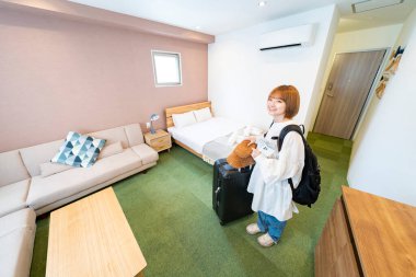 Otel odasına bakan Asyalı genç kadın.