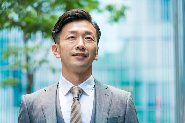 Asian businessman standing in the office district with a smile 