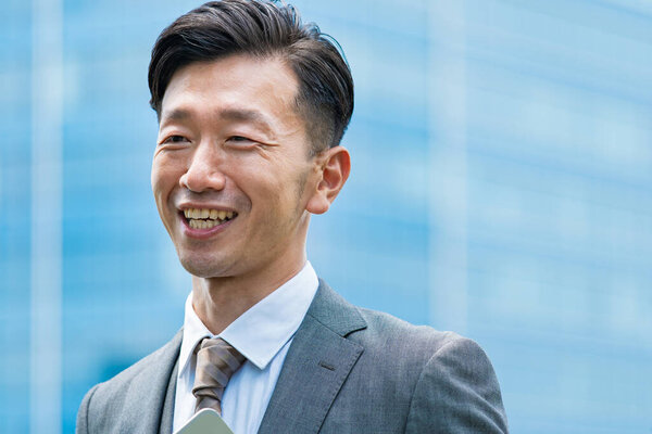 Asian businessman standing in the office district with a smile 