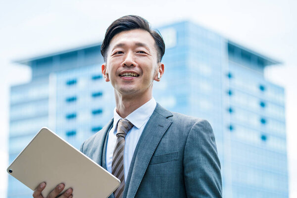 Asian businessman standing in the office district with a smile 