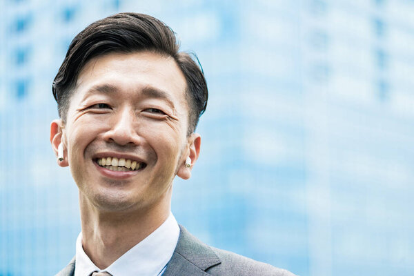 Asian businessman standing in the office district with a smile 