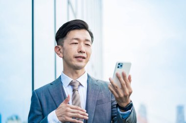 Asyalı işadamı akıllı telefon ekranına bakıyor