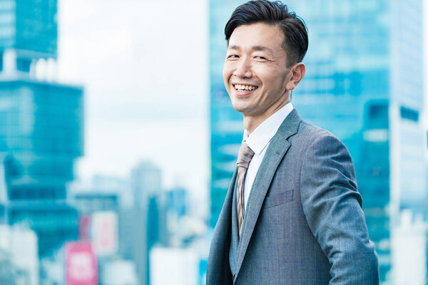 Asian businessman standing in the office district with a smile 