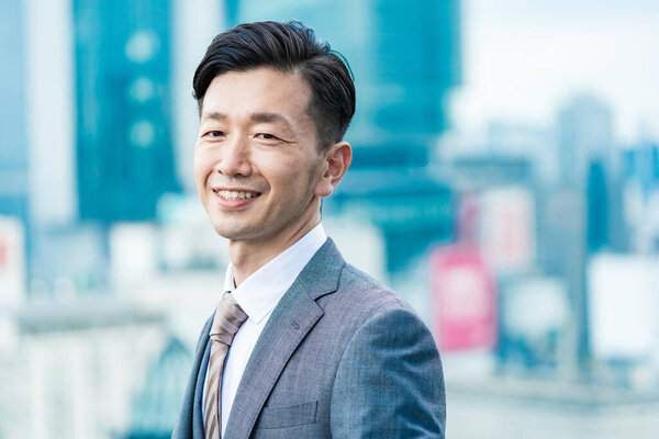Asian businessman standing in the office district with a smile 