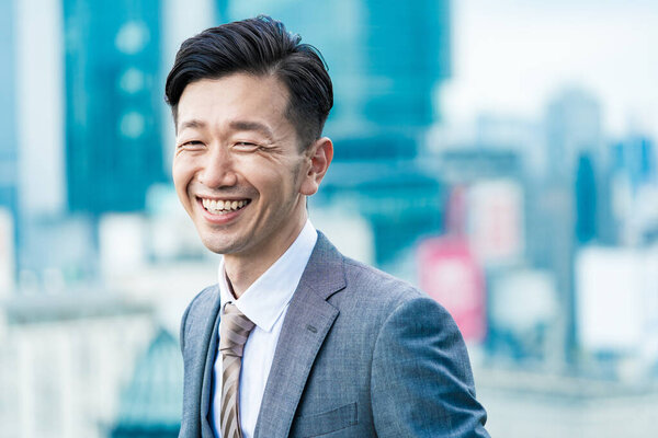 Asian businessman standing in the office district with a smile 