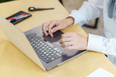 Sıradan bir yerde dizüstü bilgisayar kullanan genç bir adamın yakın çekimi.