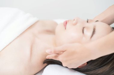 Kafası estetik bir salonda masaj yapılan Asyalı genç bir kadın.