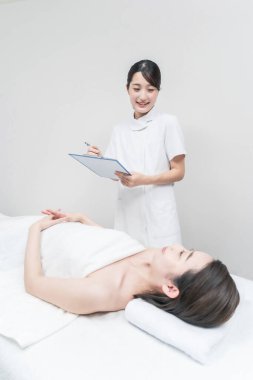 Estetik salonundaki Asyalı kadın personel danışmanlık hizmeti veriyor.