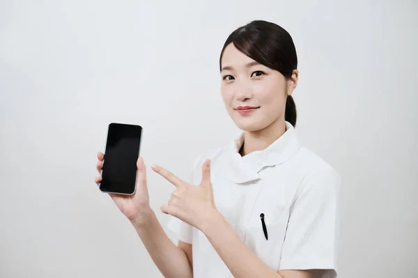 スマートフォンを操作する白いコートのアジアの女性 — ストック写真
