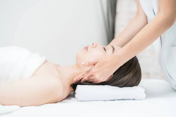 Asian young woman whose head is massaged at an esthetic salon