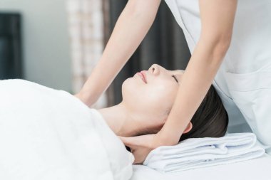 Kafası estetik bir salonda masaj yapılan Asyalı genç bir kadın.