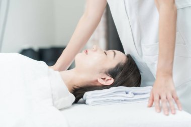 Asyalı genç bir kadın estetik bir salonda masaj yaptırıyor.
