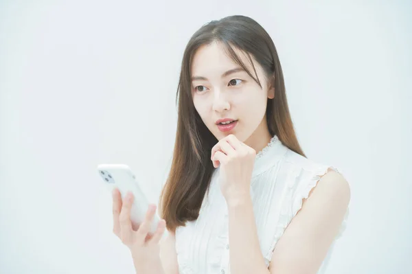 不快な気持ちでスマートフォンを見ている若い女性 — ストック写真