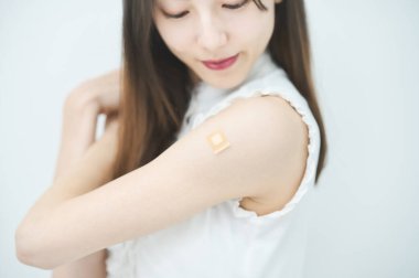 Aşı bandı takmış genç bir kadın kolu.