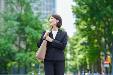 Asyalı iş kadını güzel bir günde dışarıda gülümsüyor.