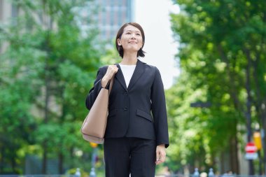 Asyalı iş kadını güzel bir günde dışarıda gülümsüyor.