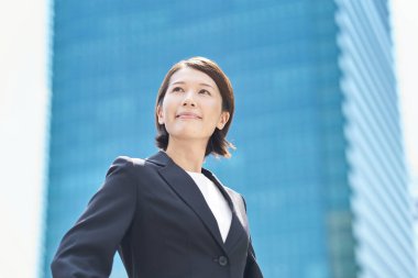 Asyalı iş kadını güzel bir günde dışarıda gülümsüyor.