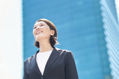 Asyalı iş kadını güzel bir günde dışarıda gülümsüyor.