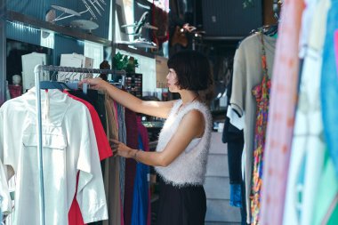 İkinci el giyim mağazasında rafları düzenleyen genç bir bayan personel.