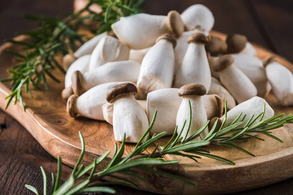 Tahtada çiğ kral istiridye mantarı ve rosmary resmi.