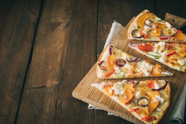 Kabaklı tarte flambee parçaları, kırmızı soğan ve peynir kırsal ahşap masa üzerinde fotokopi alanı ile