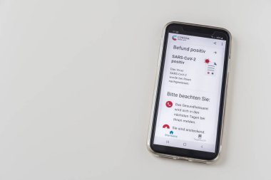 Almanya - 27 Mart 2021: Covid-19 SARS-CoV-2 test sonuçlu akıllı telefon Robert Koch Enstitüsü 'nün resmi Alman Corona uyarı uygulaması, beyaz arkaplan, kopyalama uzayı. Befund Positiv: Sonuç pozitif, Bitte Beachten Sie: Lütfen dikkat edin.