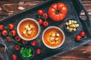 Ahşap zemin üzerinde ahşap bir tepside taze ev yapımı domates çorbası ile dolu iki fincan.