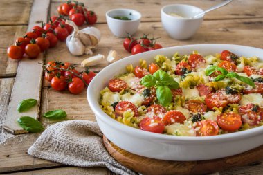 Fesleğen soslu makarna güveci, domates ve mozzarella, vejetaryen, eski ahşap bir masada.